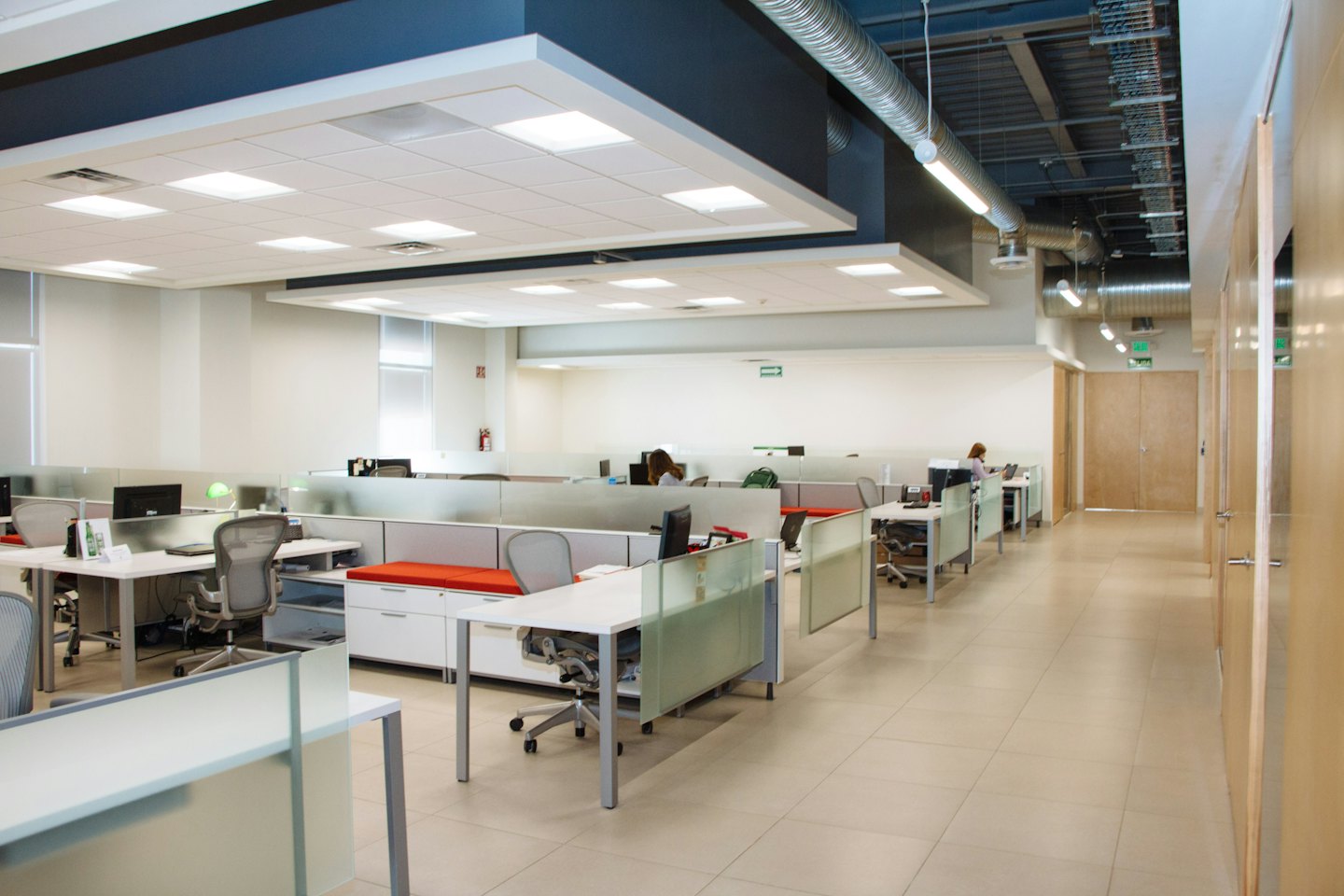 Bright open-plan office with cubicles and employees working.