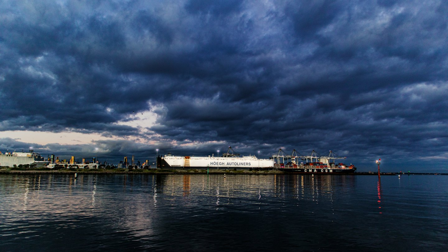 Cargo ships docked at a busy commercial port at dusk.