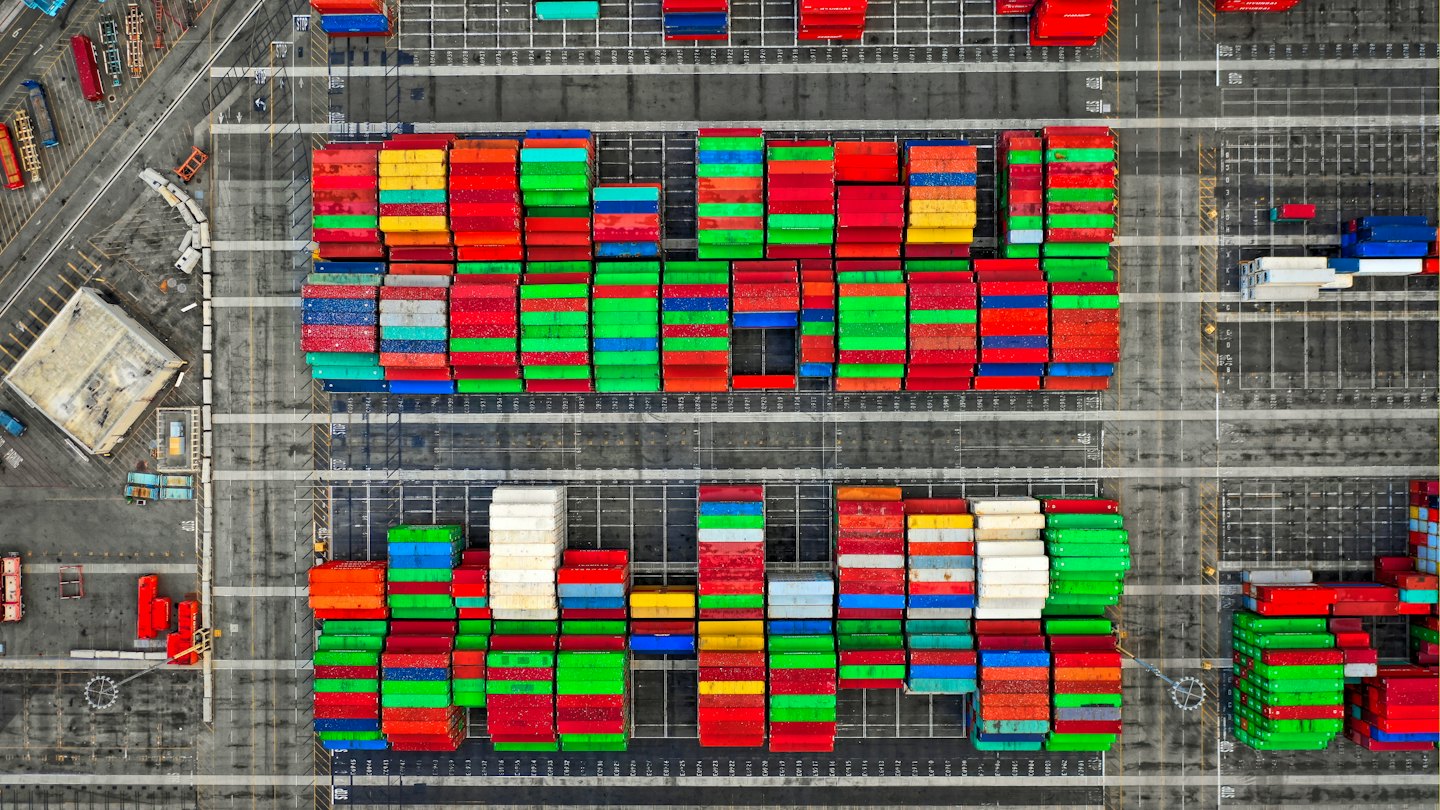 Colorful shipping containers are stacked in rows at a busy port.