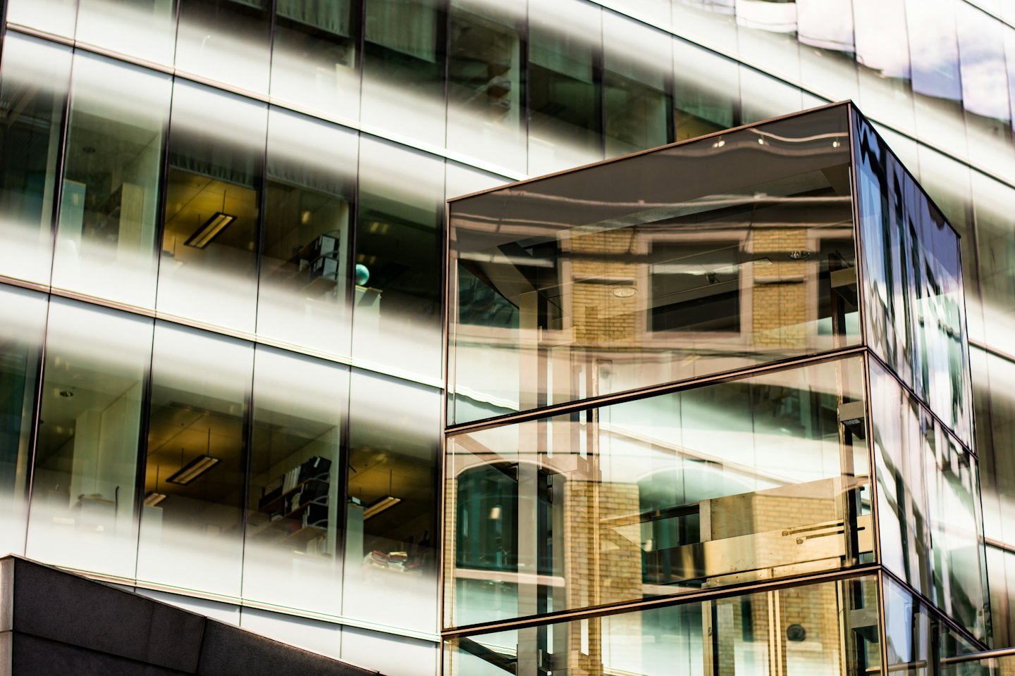 Modern glass office building reflects an older brick building.
